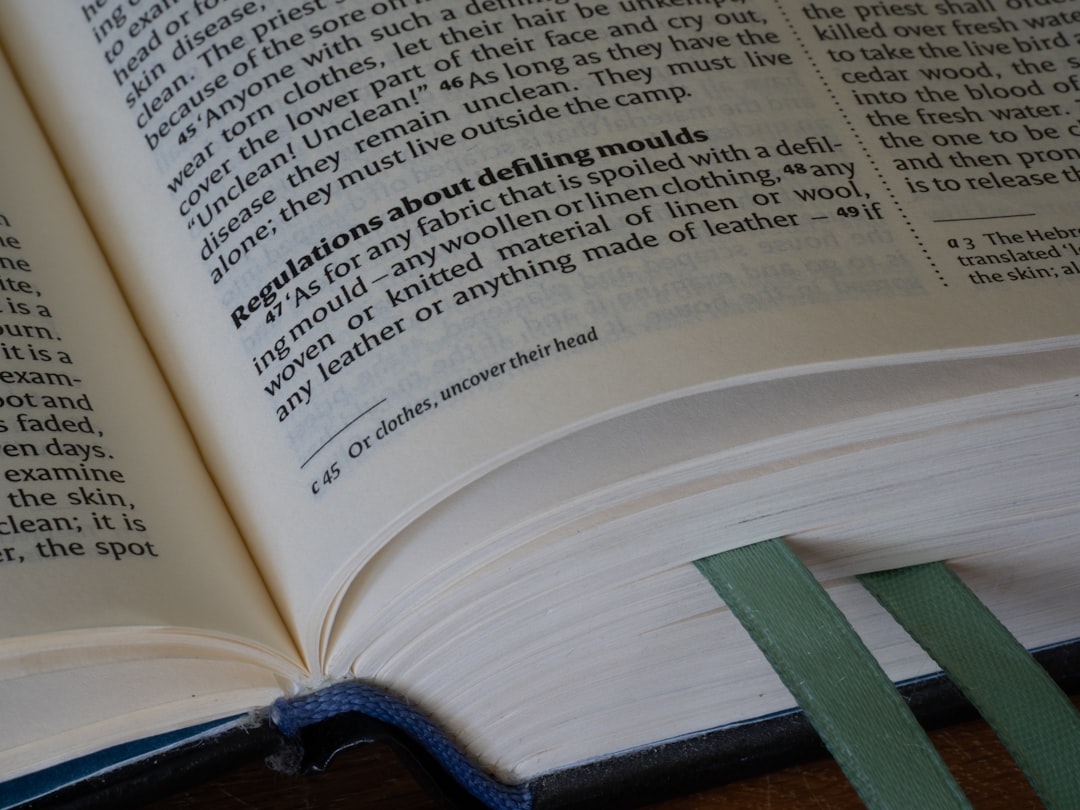 an open book with text and two green ribbon bookmarks