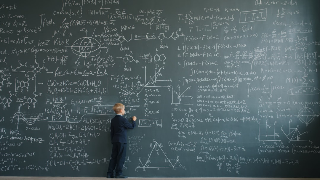 Young boy writing complex formulas on a chalkboard.