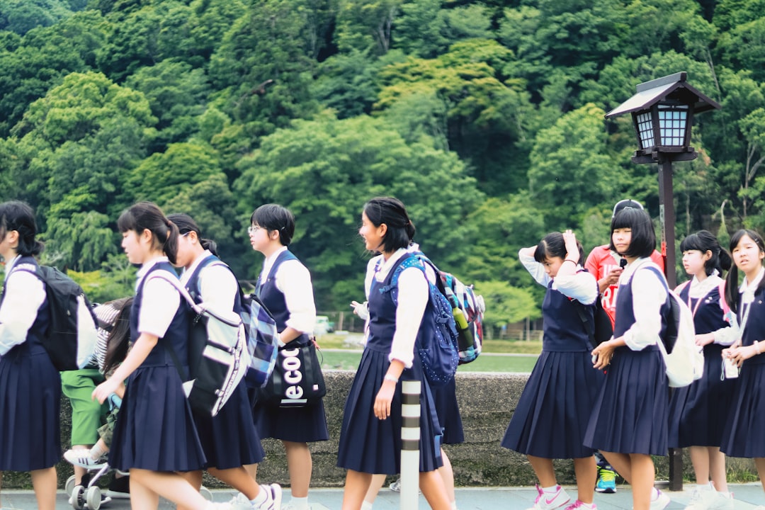 昼間の芝生の上に立つ制服姿の女子生徒たち